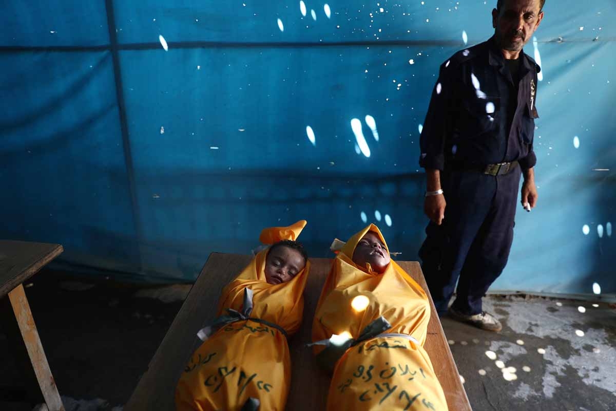 A Syrian man stands at a morgue next to the bodies of two young sisters who reportedly died after their house collapsed following a reported air stike on the rebel-held town of Douma, east of the capital Damascus, on August 22, 2016. A Syrian man stands at a morgue next to the bodies of two young sisters who reportedly died after their house collapsed following a reported air stike on the rebel-held town of Douma, east of the capital Damascus, on August 22, 2016.