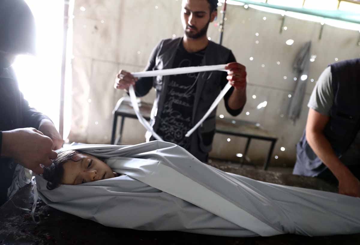 Volunteers wrap in shrouds the body of a Syrian child, Emad, 5, at a makeshift morgue following a reported air stike on the rebel-held town of Douma, east of the capital Damascus, on August 23, 2016. Volunteers wrap in shrouds the body of a Syrian child, Emad, 5, at a makeshift morgue following a reported air stike on the rebel-held town of Douma, east of the capital Damascus, on August 23, 2016.