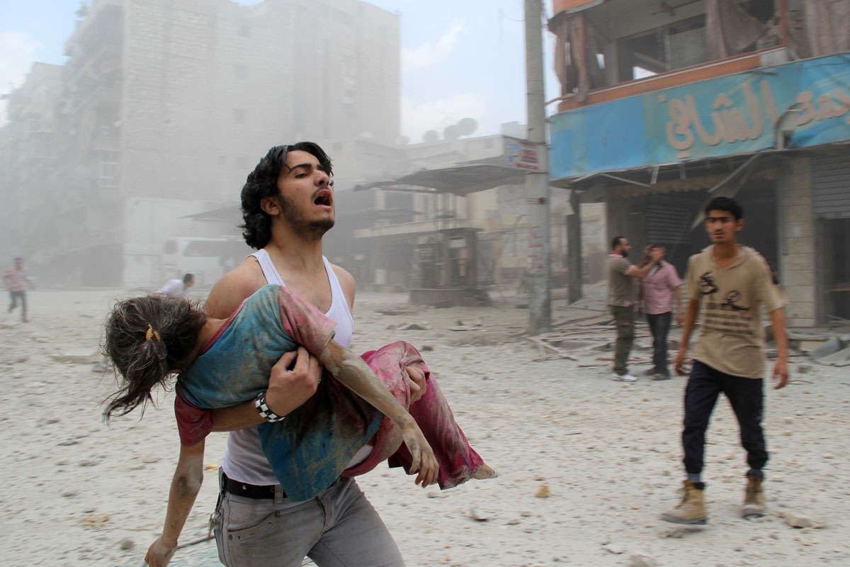 A man carries a young girl who was injured in a reported barrel-bomb attack by government forces on June 3, 2014 in Kallaseh district in the northern city of Aleppo.
