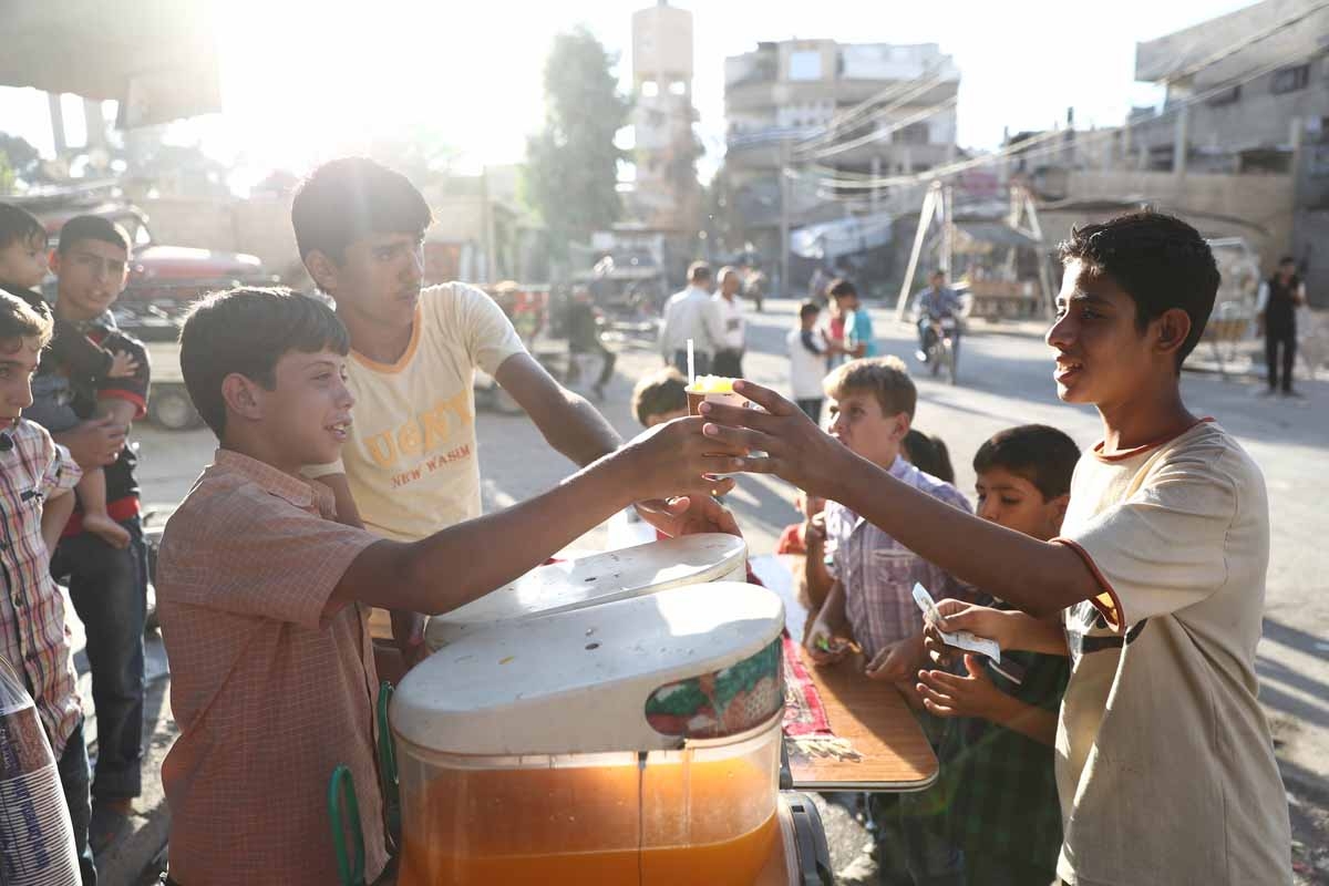 A Syrian boy serves a juice on the third day of the Al-Adha Eid (Festival of Sacrifice) Muslim holiday in the rebel-controlled town of Hamouria, in the eastern Ghouta region on the outskirts of the capital Damascus, on the second day of an internally back