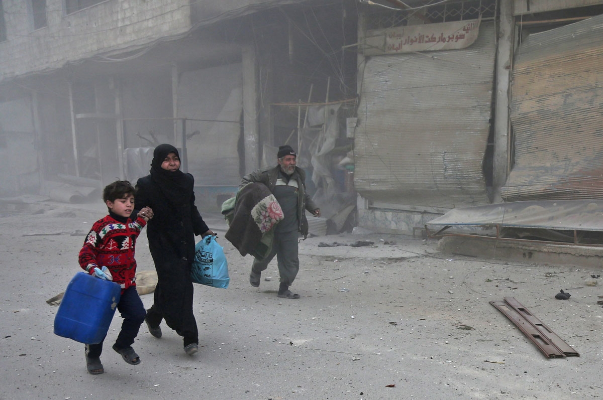 Syrians run for cover in Hamouria during Syrian government shelling on rebel-held areas in the Eastern Ghouta region on the outskirts of the capital Damascus on March 6, 2018. Heavy air strikes and clashes shook the Syrian rebel enclave of Eastern Ghouta,