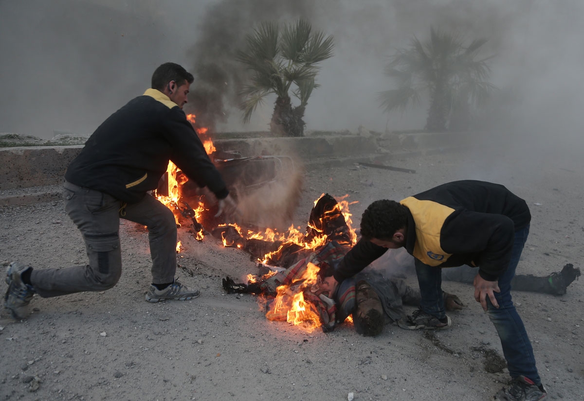Syrian aid workers try to put out a fire engulfing a man fatally wounded in the bombardment in Hammuriyeh, March 7, 2018.