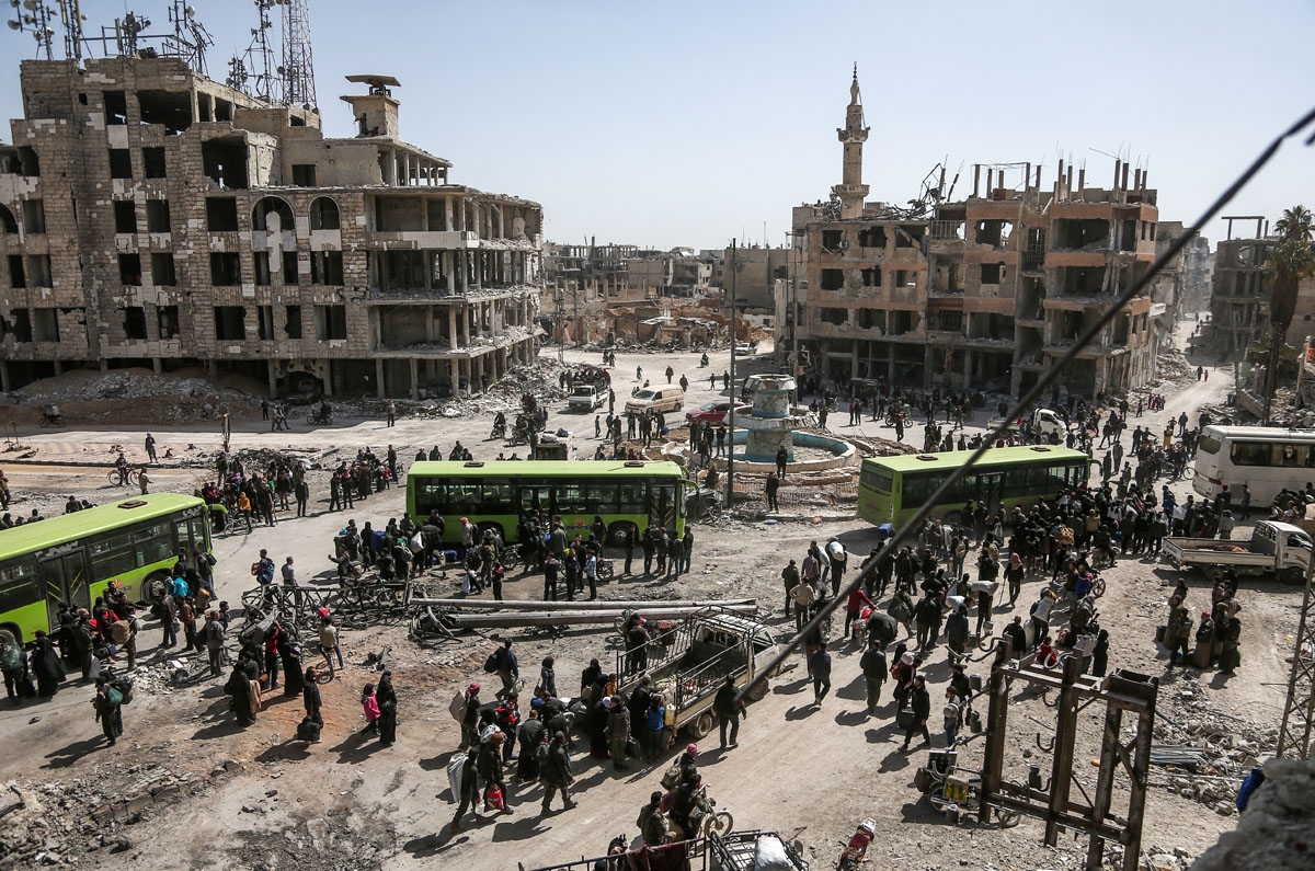 Syrian civilians and rebel fighters prepare to embark aboard buses during the evacuation from the town of Arbin in the Eastern Ghouta region on the outskirts of the capital Damascus on March 25, 2018 after a deal was struck with the regime