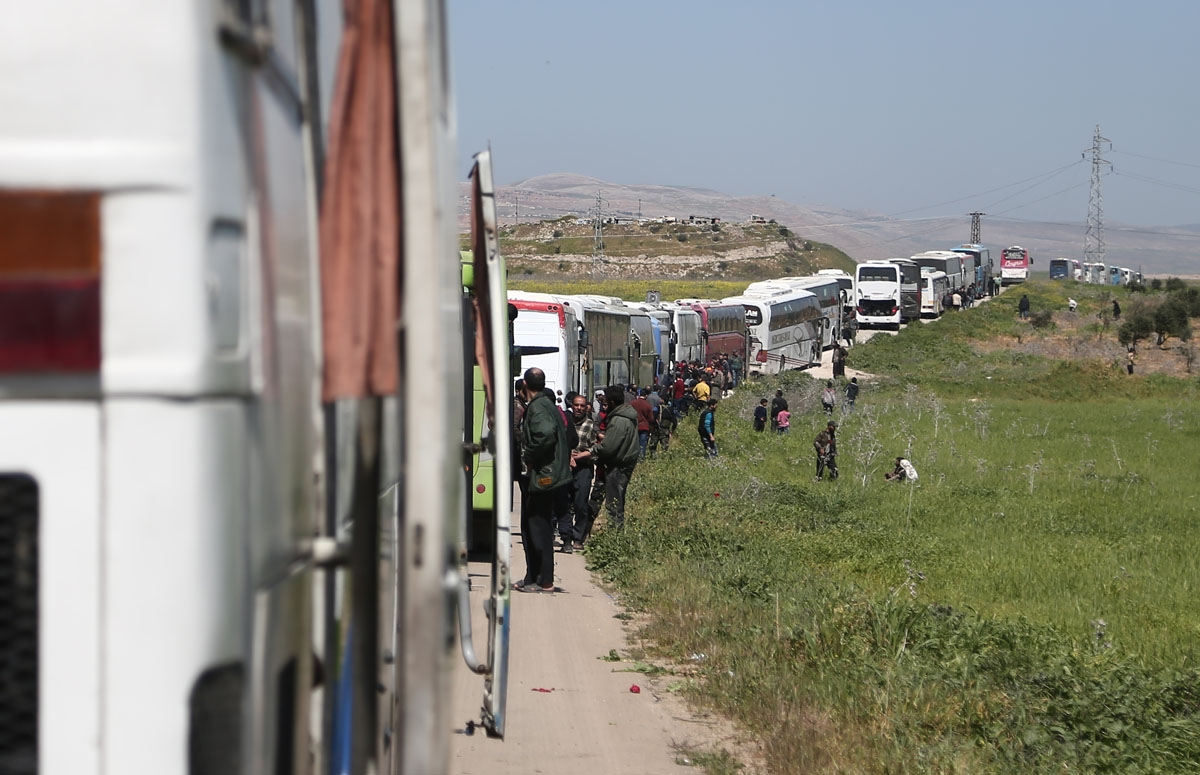 A convoy transporting Syrian civilians and rebel fighters evacuated from Eastern Ghouta waits in a government-held area prior to entering the village of Qalaat al-Madiq, some 45 kilometres northwest of the central city of Hama, on March 26, 2018, as evacu