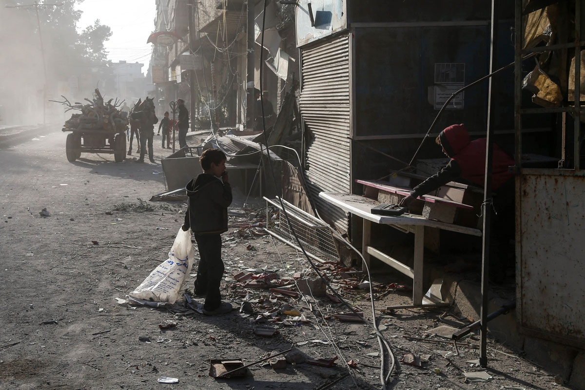Syrian children clean up their shop from debris following reported regime air strikes in the rebel-held town of Kafr Batna, in the besieged Eastern Ghouta region on the outskirts of the capital Damascus, on February 6, 2018.
