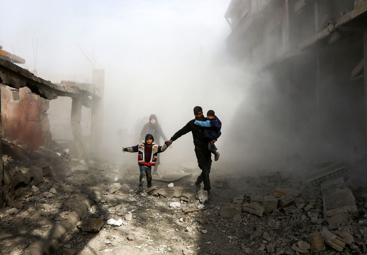 Syrian civilians flee from reported regime air strikes in the rebel-held town of Jisreen, in the besieged Eastern Ghouta region on the outskirts of the capital Damascus, on February 8, 2018.