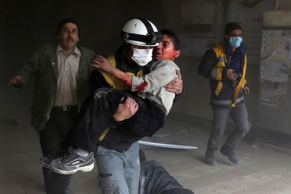A member of the Syrian civil defence carries a wounded child from the rubble after a reported regime air strike in the rebel-held town of Jisreen, in the besieged Eastern Ghouta region on the outskirts of the capital Damascus, on February 8, 2018.
