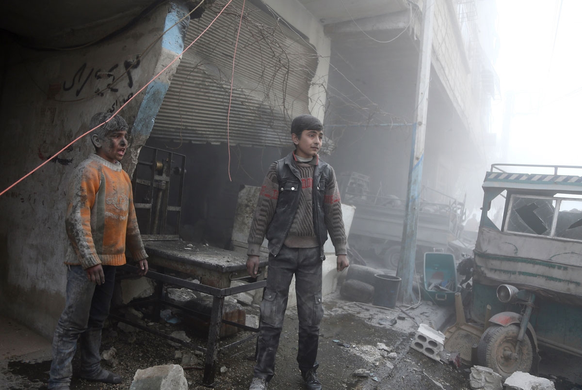 Syrian children covered in dust walk out of a shop following reported Syrian air force strikes in the rebel-held town of Saqba, in the besieged Eastern Ghouta region on the outskirts of the capital Damascus on February 8, 2018.
