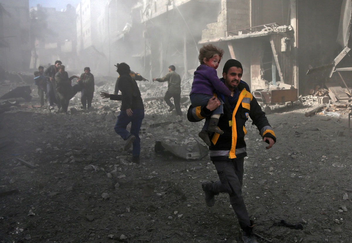 A Syrian man carries an infant rescued from the rubble of buildings following government bombing in the rebel-held town of Hamouria, in the besieged Eastern Ghouta region on the outskirts of the capital Damascus, on February 19, 2018.