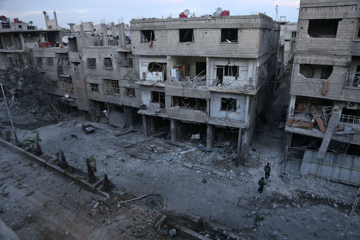 Syrian civilians look at the rubble following government bombing in the rebel-held town of Hamouria, in the besieged Eastern Ghouta region on the outskirts of the capital Damascus, on February 19, 2018.