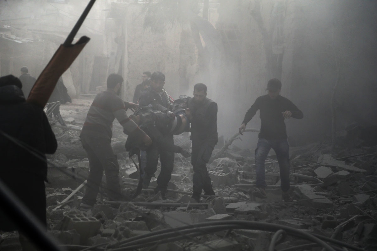 Members of the Syrian civil defence evacuate an injured civilian from an area hit by a reported regime air strike in the rebel-held town of Saqba, in the besieged Eastern Ghouta region on the outskirts of the capital Damascus, on February 20, 2018.