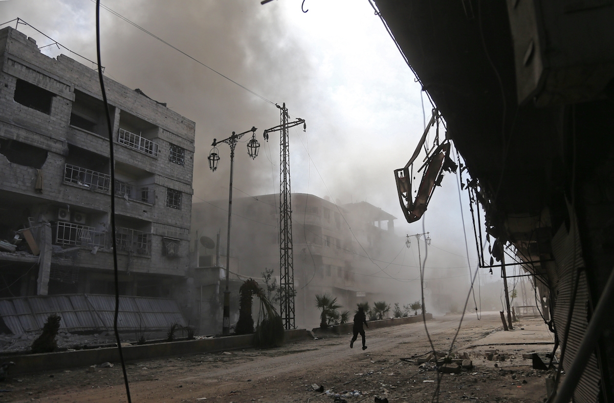 Smoke and dust are seen following a reported regime air strike in the rebel-held town of Hamouria, in the besieged Eastern Ghouta region on the outskirts of the capital Damascus on February 21, 2018.