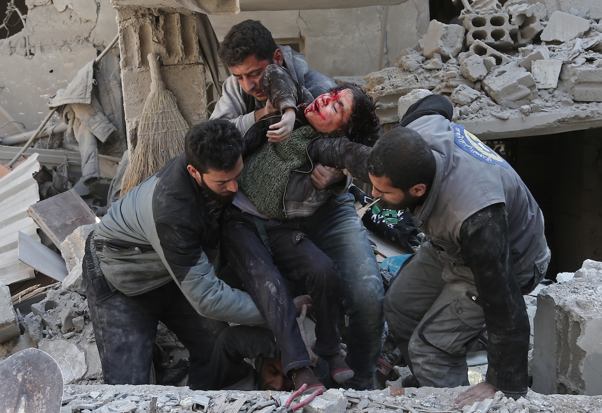 EDITORS NOTE: Graphic content / Syrians rescue a child following a reported regime air strike in the rebel-held town of Hamouria, in the besieged Eastern Ghouta region on the outskirts of the capital Damascus on February 21, 2018.