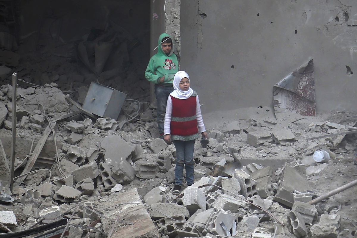 Syrian children stand amidst debris in Hamouria, in the rebel-held besieged Eastern Ghouta region on the outskirts of the capital Damascus on February 22, 2018.