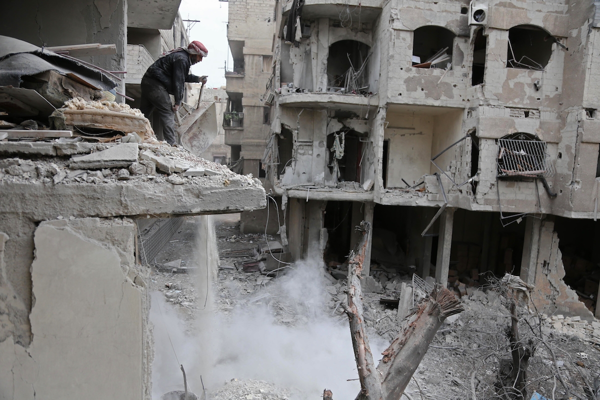 A Syrian man checks the site of Syrian government bombardments in Hamouria, in the besieged Eastern Ghouta region on the outskirts of the capital Damascus on February 22, 2018.