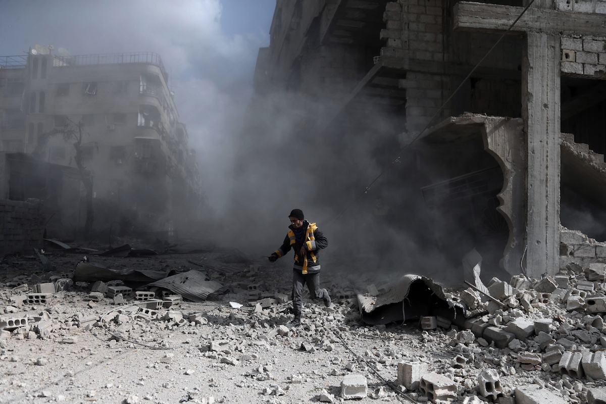 A civil Defence volunteer, known as the White Helmets, checks the site of a regime air strike in the rebel-held town of Saqba, in the besieged Eastern Ghouta region on the outskirts of the capital Damascus, on February 23, 2018.