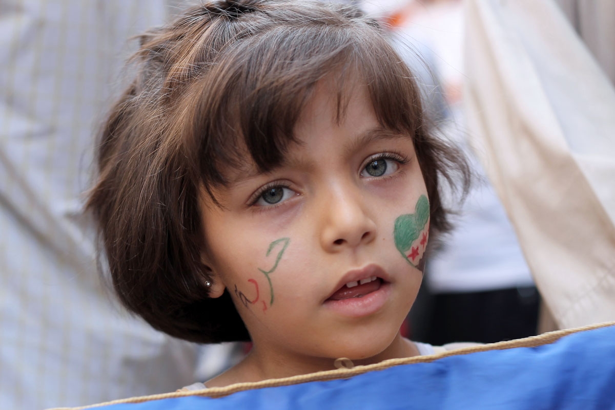 A girl with the colours of the Syrian revolutionary flag painted on her cheek takes part in an anti-government demonstration in the Bustan al-Qasr neighbourhood of northern Syrian city of Aleppo on October 4, 2013.