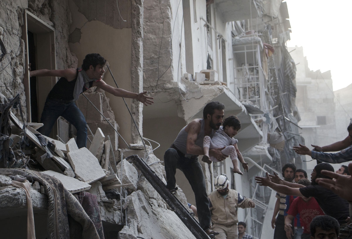 A man evacuates a child from a building following a reported barrel bomb attack by Syrian government forces on the northern Syrian city of Aleppo, on May 30, 2015. Barrel bombs dropped from regime helicopters killing more than 70 civilians in Aleppo, whil
