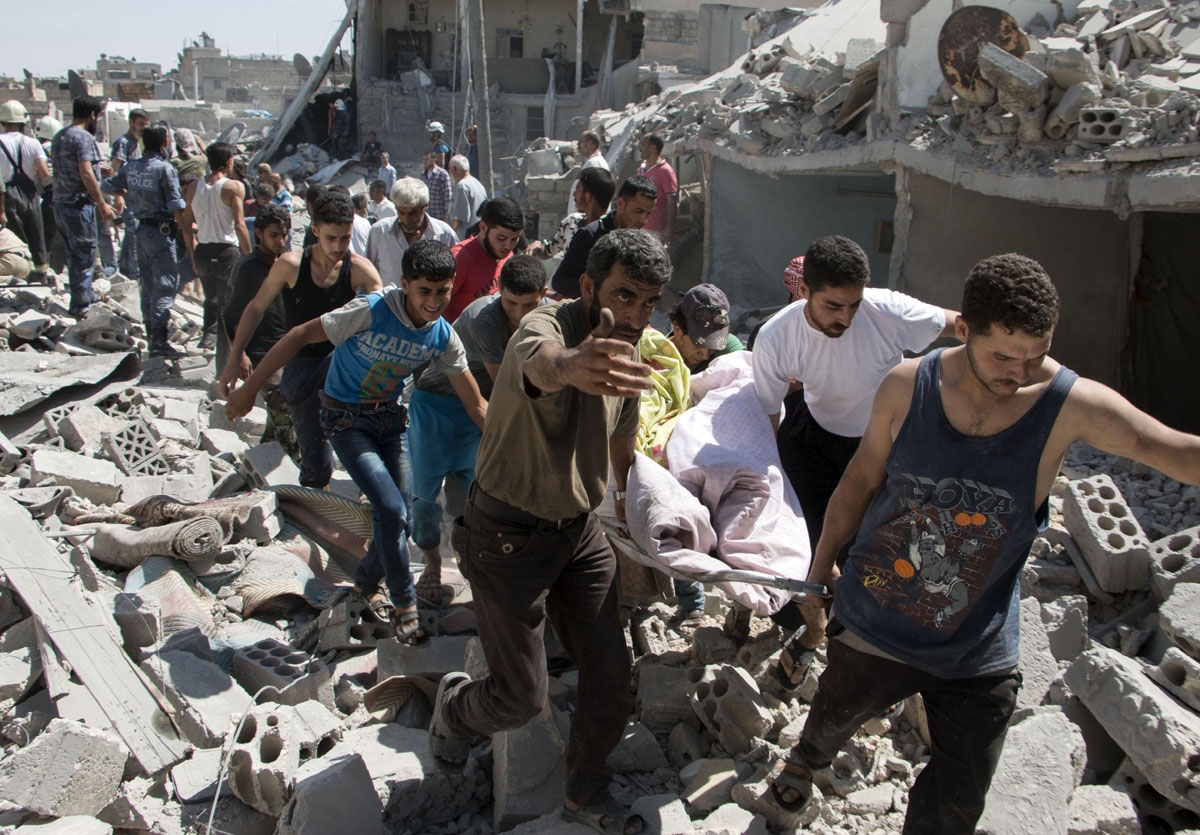 Syrians carry a body on a stretcher over the rubble after a missile fired by Syrian government forces hit a residential area in the Maghayir district in the old quarter of the northern Syrian city of Aleppo on July 21, 2015. According to the Syrian Observ