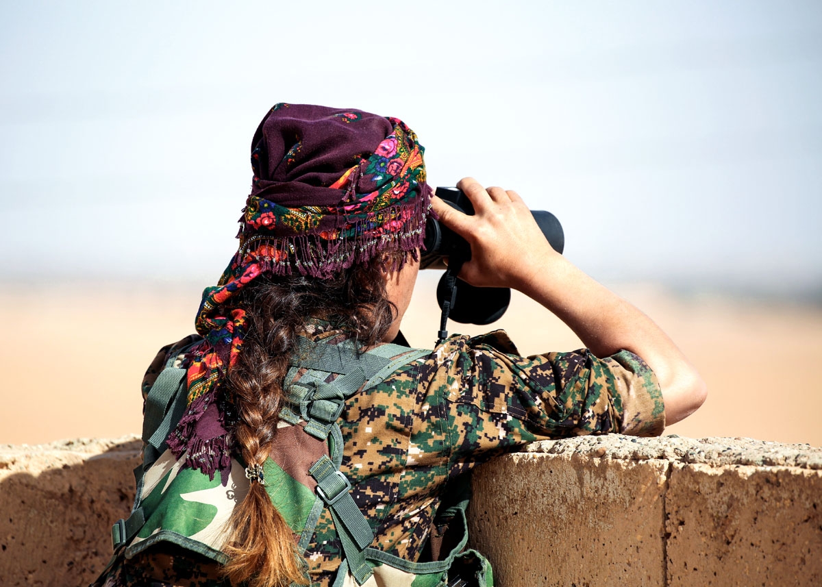 Shirin, 25, a member of the Kurdish female Women's Protection Units (YPJ) views the battlefield with binoculars from atop a house in the Syrian village of Mazraat Khaled, some 40 kms away from the Islamic State group's (IS) de-facto capital of Raqa on Nov