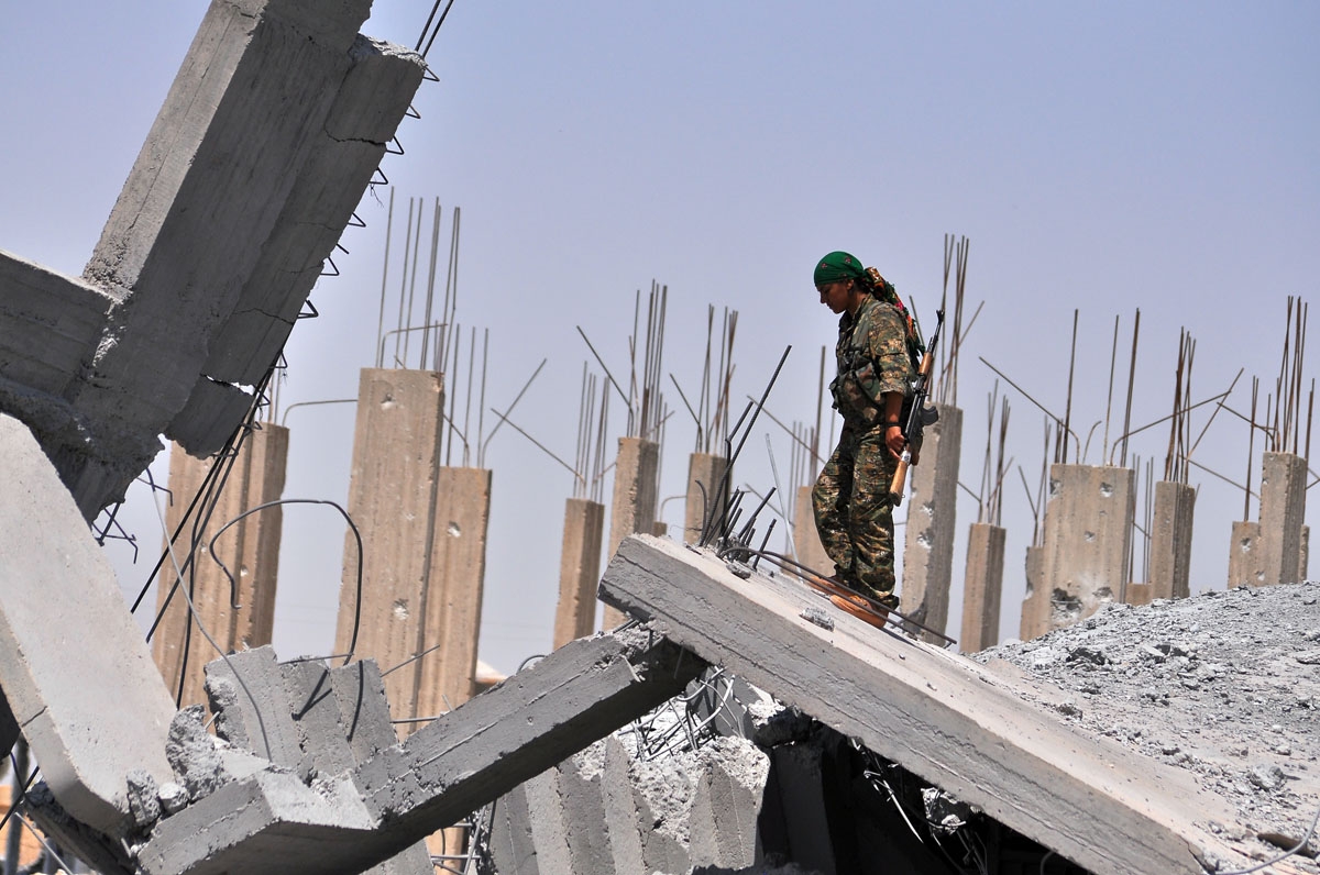 A female fighter from the Kurdish People Protection Unit (YPG) looks at destruction in the Syrian town of Ain Issi, some 50 kilometres north of Raqqa, the self-proclaimed capital of the Islamic State (IS) group during clashes between IS group jihadists an