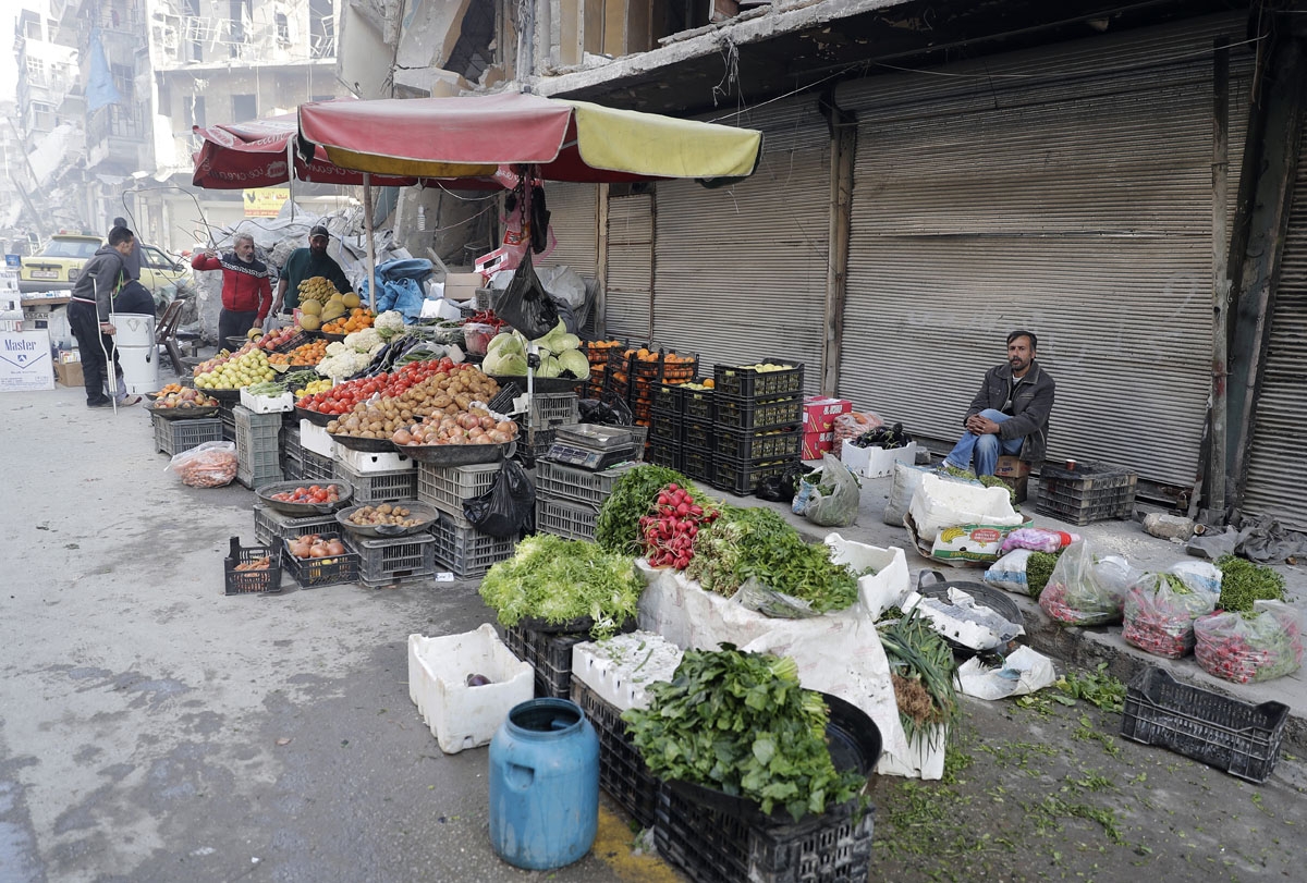 A picture taken on March 9, 2017 in the northern Syrian city of Aleppo, which was recaptured by government forces in December 2016, shows people purchasing vegetables in the formerly rebel-held al-Shaar neighbourhood.