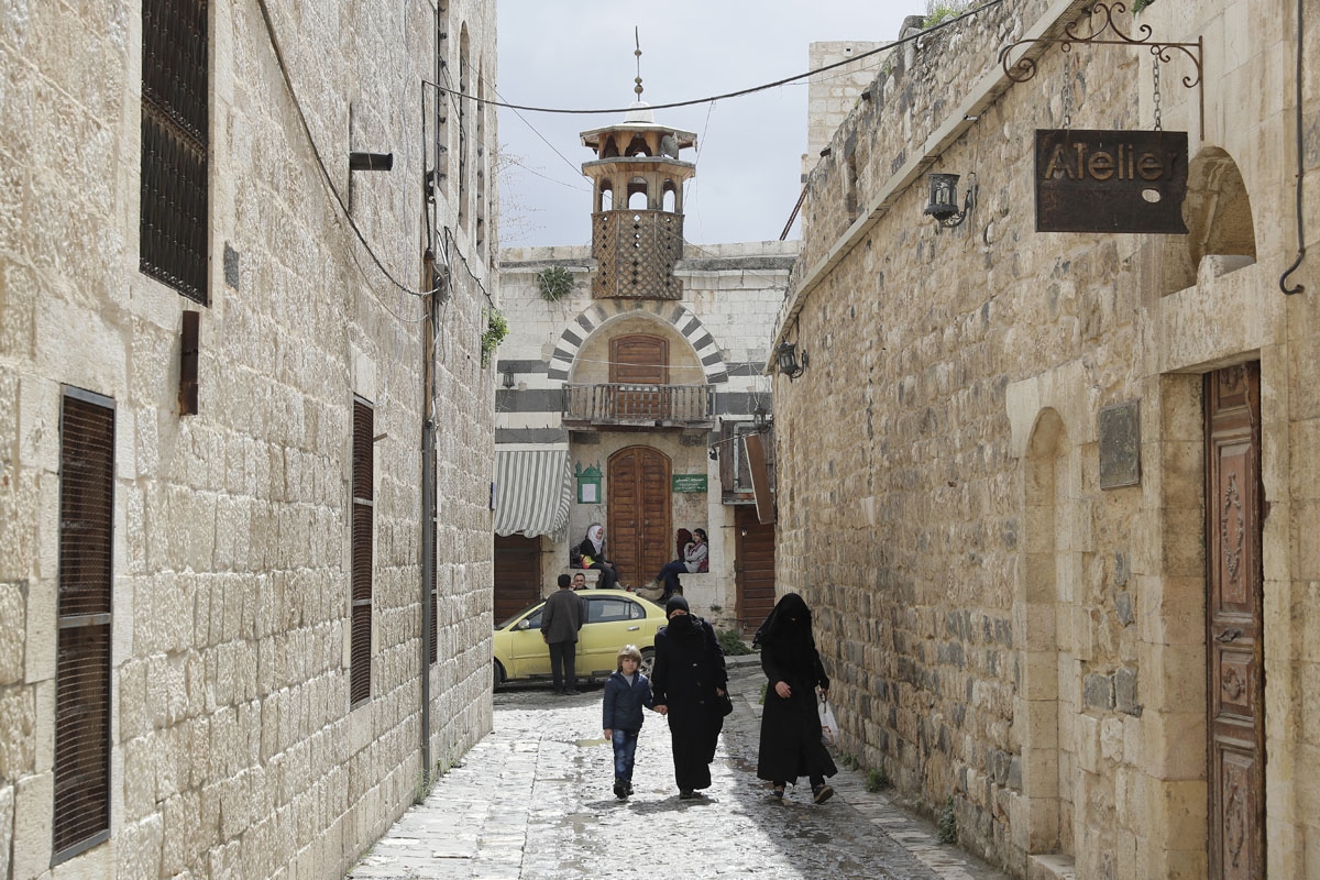 People walk through an alley in the old city of Hama, in central Syria, on March 13, 2017.