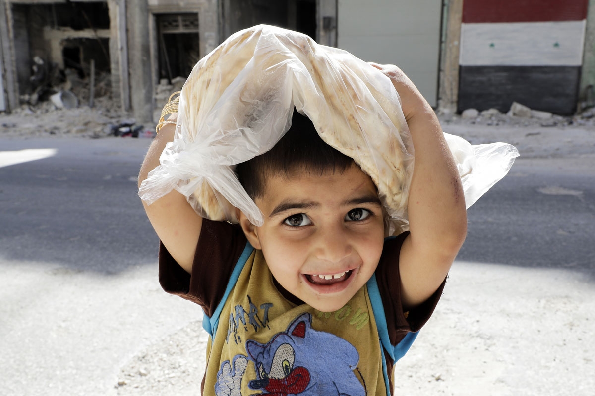 A Syrian boy carries a bag filled with bread while on his way home, in the Kallaseh district of the northern city of Aleppo, on July 5, 2017.