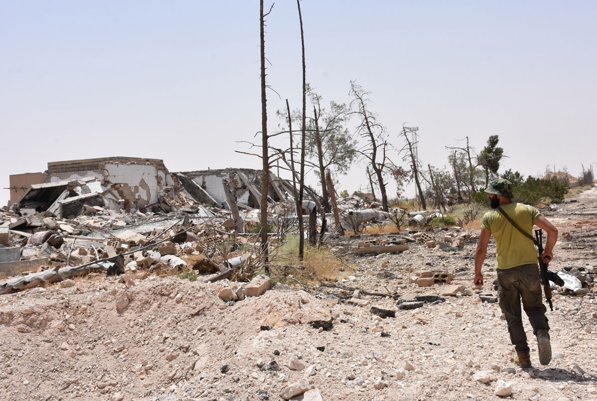 A member of Syria's pro-regime force inspects an area recently recaptured from the Islamic State (IS) group in a mountain range near the village of Khanasser, in the Aleppo governorate, on July 2, 2017.