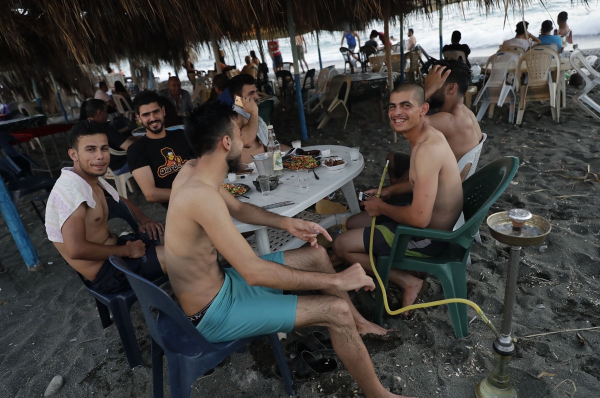 Syrians spend time on the shores of the Mediterranean Sea in Wadi Qandil north of the seaside city of Latakia on July 6, 201