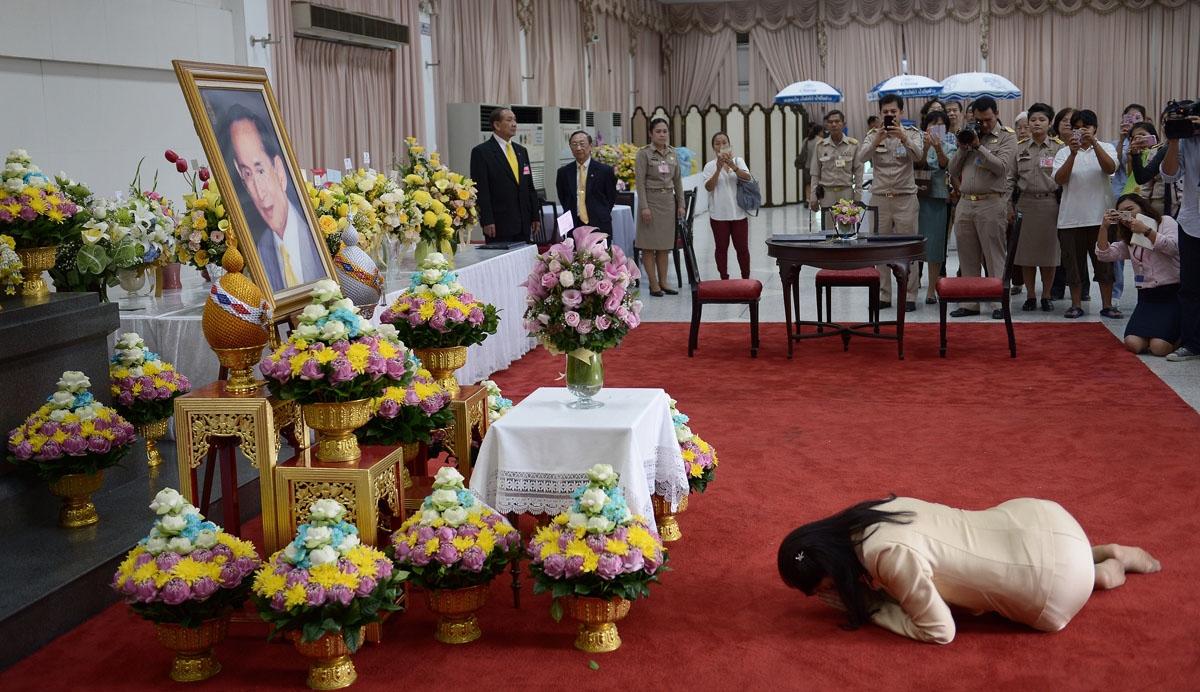 Ousted Thai prime minister Yingluck Shinawatra bows to a portrait of Thai King Bhumibol Adulyadej as she pays her respects during a visit at the Siriraj hospital in Bangkok on October 6, 2014. Thailand's revered 86-year-old King Bhumibol Adulyadej has had