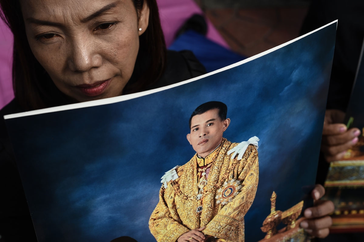 A woman holds an image of Thailand's new King Maha Vajiralongkorn outside the Grand Palace in Bangkok on December 2, 2016.