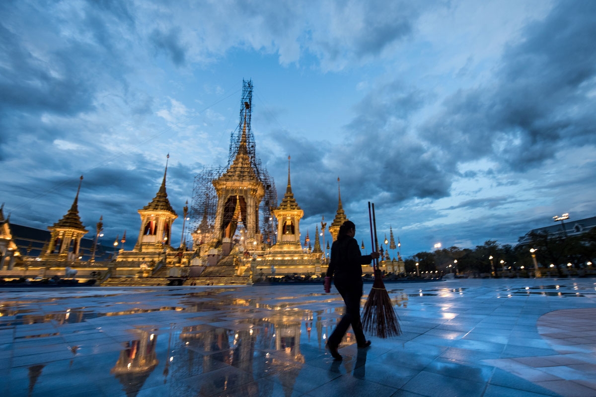 In this October 17, 2017 photo, a worker carries a broom on the grounds of the cremation site for Thailand's late king Bhumibol Adulyadej.