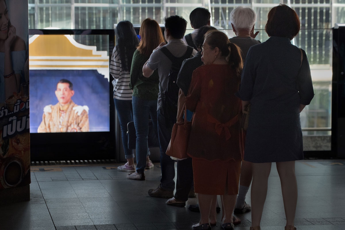 Commuters riding the metro train line up to wait for the next train near a portrait of Thai King Maha Vajiralongkom on October 30, 2017.