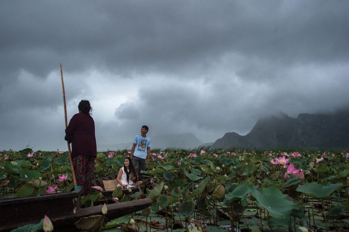 In this photograph taken on May 5, 2017, tourists look at lotus flowers while on a canoe on a lake in the Khao Sam Roi Yot national park in southern Thailand.