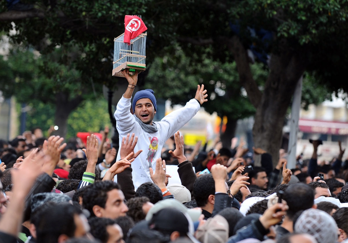 A Tunisian demonstrator, holds a cage and the national country flag, during a rally on January 14, 2011 outside the Interior ministry in Tunis, demanding President Zine El Abidine Ben Ali's resignation.