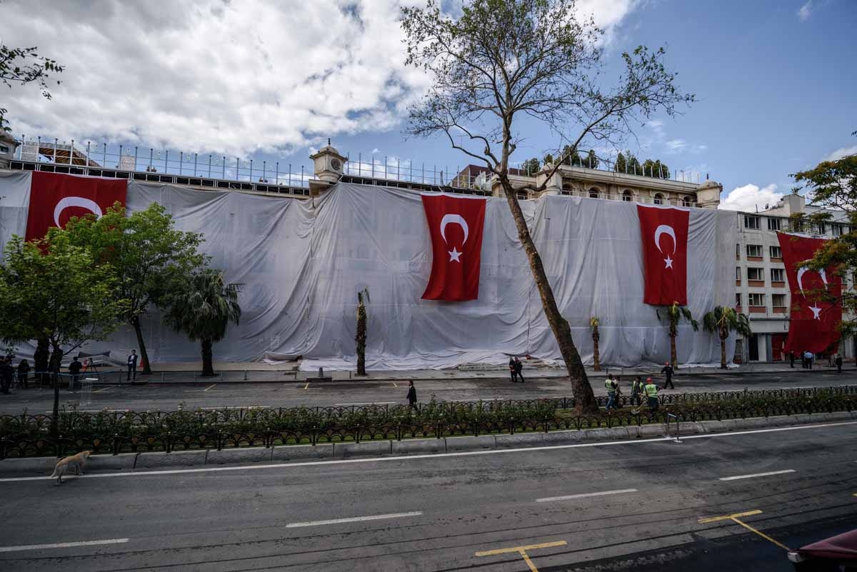 People walk in front of a hotel covered with a tarpaulin and Turkish national flags, a day after a bombing killed 11 people including several police officers, in the Vezneciler district of Istanbul, on June 8, 2016.