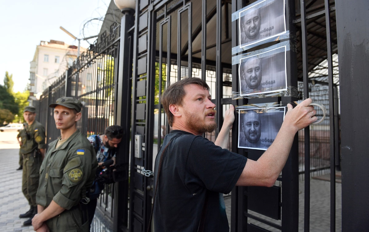 An activists hangs portraits of journalist Arkadi Babchenko to the fence of Russian embassy in Kiev, on May 30, 2018, one day after he was alleged to have been shot in his apartment building in the Ukrainian capital.