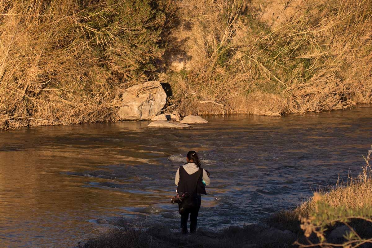 A woman crosses the Rio Bravo with a baby in her arms trying to reach the US city of Presidio (background) near to the international bridge on the US/Mexico border in Ojinaga, on February 20, 2017, northern Mexico