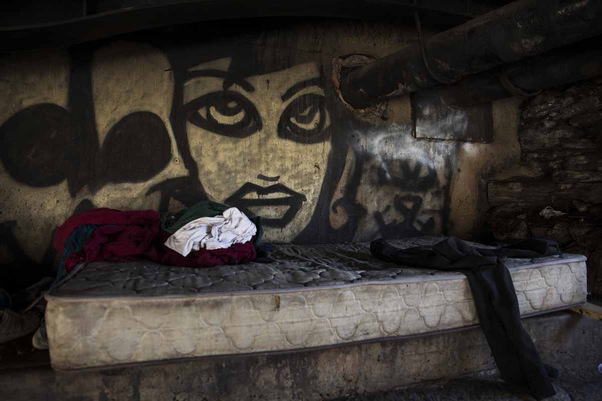 A graffiti portrait looks out from behind a mattress in the Kensington neighborhood of Philadelphia, Pennsylvania, on April 10, 2017