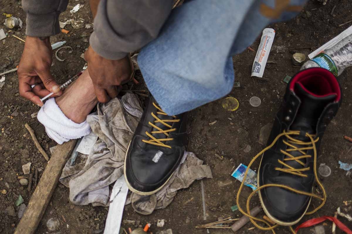 A man injects himself in the foot with heroin near a heroin encampmentin the Kensington neighborhood of Philadelphia, Pennsylvania, on April 14, 2017