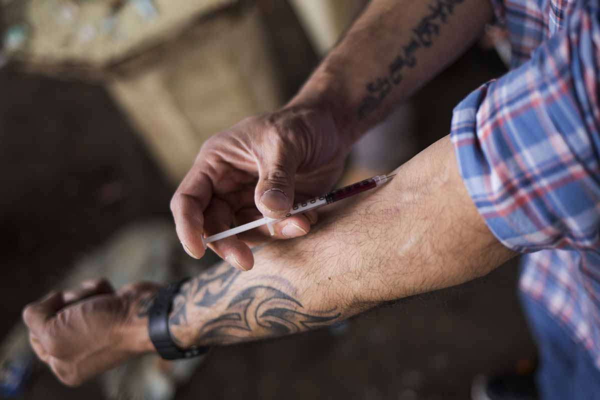 A man injects a shot of heroin near a heroin encampmentin the Kensington neighborhood of Philadelphia, Pennsylvania, on April 14, 2017.