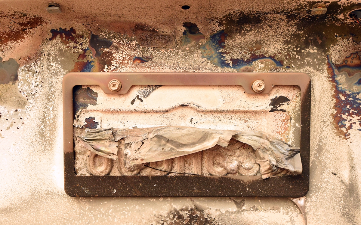 A partially melted license plate hangs on an abandoned burned-out vehicle on the side of a road in Paradise, north of Sacramento, California on November 09, 2018.