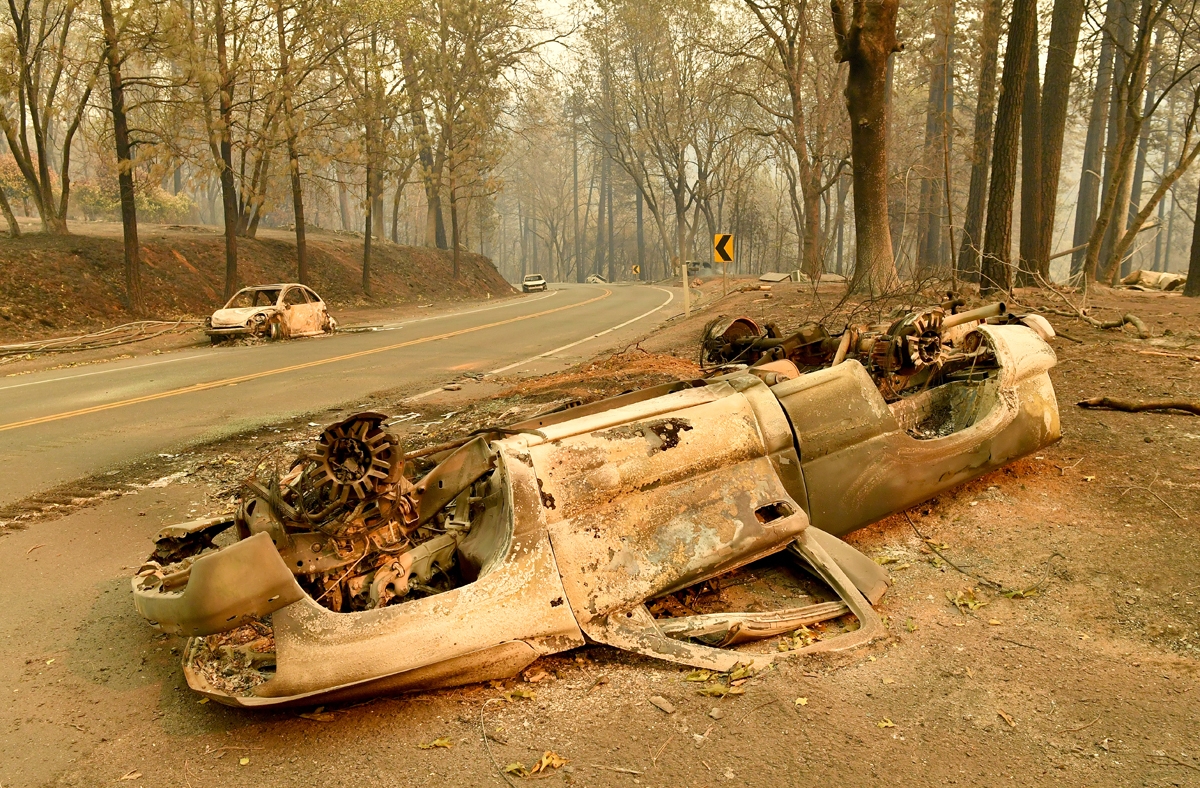Burned cars litter a road during the Camp fire in Paradise, California on November 12, 2018.