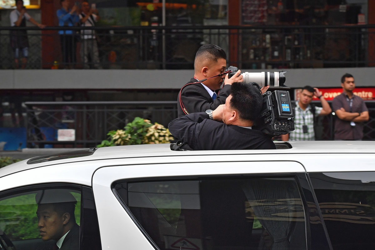 North Korean journalists take images from their vehicle's sunroof of the car behind transporting North Korea's leader Kim Jong Un in Singapore, June 12, 2018.