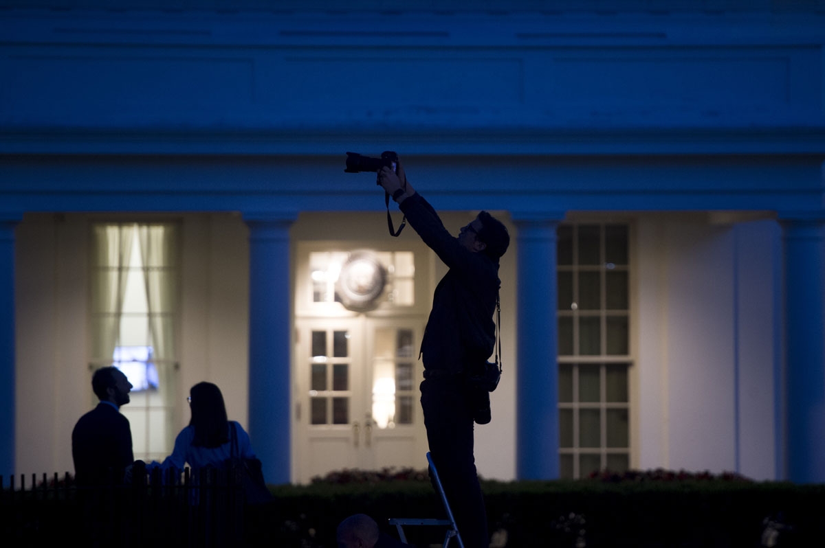 Reporters and photographers work outside of the West Wing of the White House at dusk in Washington, DC, May 15, 2017.