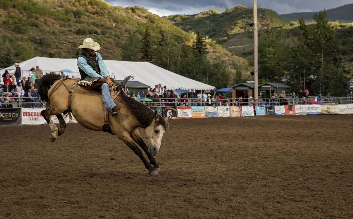A cowboy rides a bucking bronco at the Snowmass Rodeo on August 22, 2018, in Snowmass, Colorado.