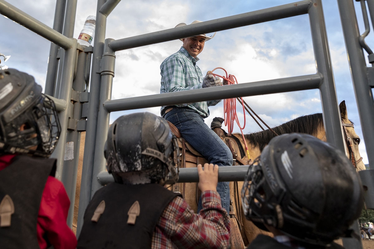 A cowboy smiles at children as they prepare for the mutton bustin' event at the Snowmass Rodeo on August 22, 2018, in Snowmass, Colorado.