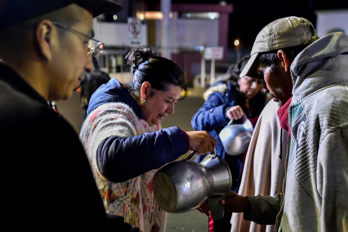 Colombians offer food to Venezuelan migrants waiting outside the Ecuadorean migration office at the Rumichaca international bridge in Tulcan, Ecuador, August 20, 2018.