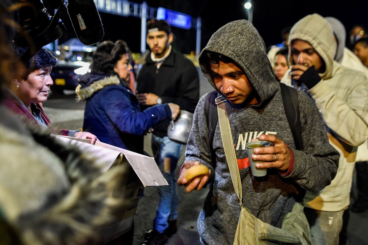 Colombians offer food to Venezuelan migrants waiting outside the Ecuadorean migration office at the Rumichaca international bridge in Tulcan, Ecuador, August 20, 2018.